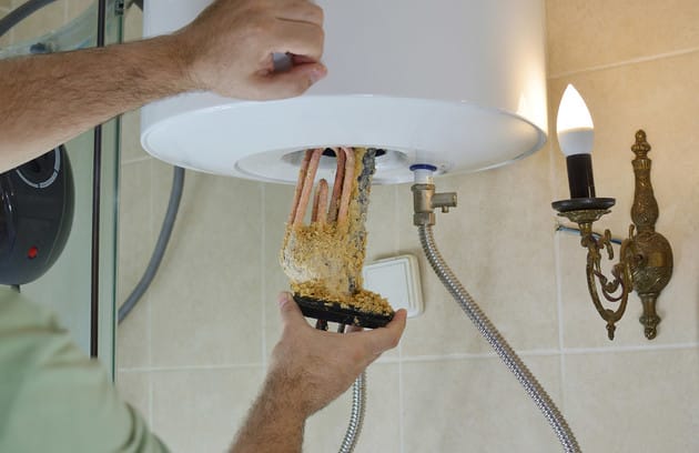 Technician removing mineral buildup from a water heater in Greeley
