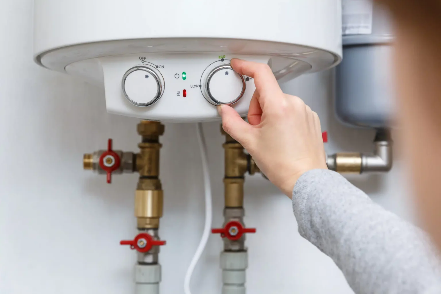 Homeowner adjusting the temperature controls on a water heater in Greeley